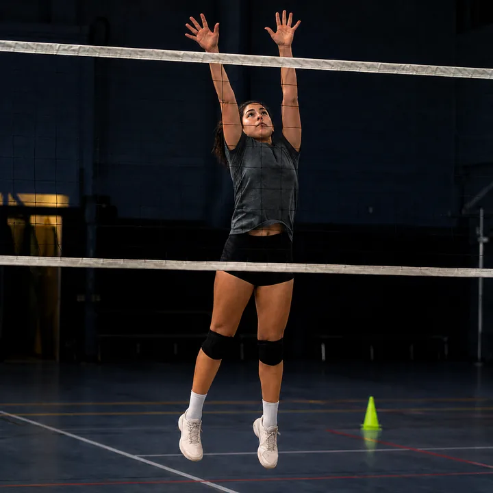 A volleyball player at the top of a block jump at the net