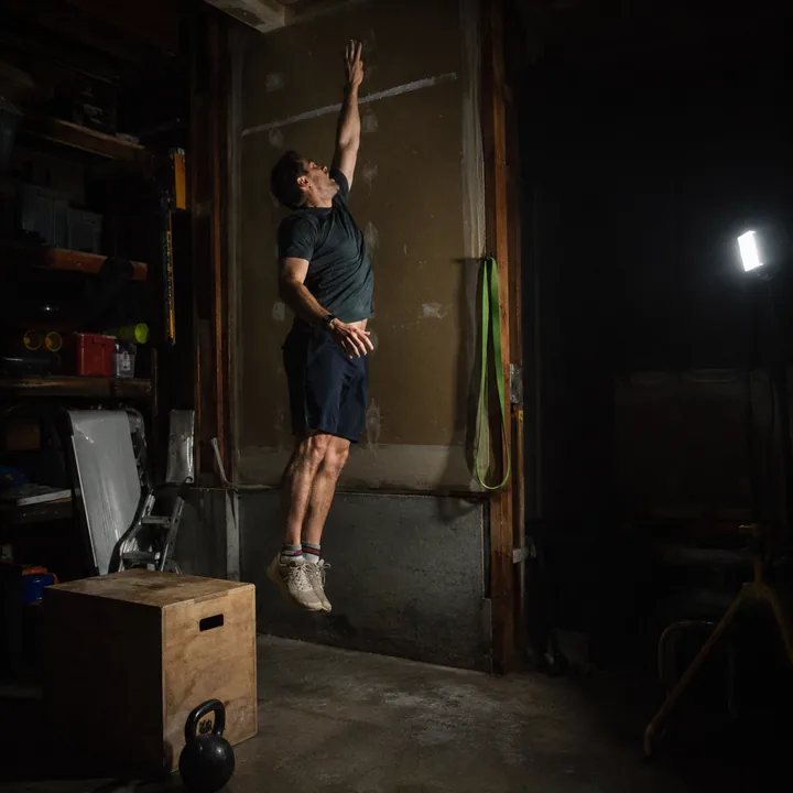 A person jumping to touch a chalk mark in a garage home gym